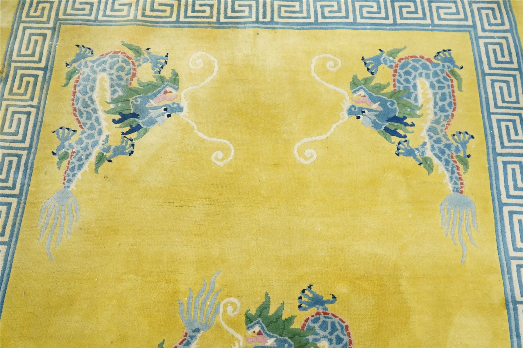 Modern Chinese hand-knotted wool pile carpet, golden field decorated with conforming dragons amidst stylized cloud scrolls enclosed by a Greek gey meander border, with cotton fringe ends 