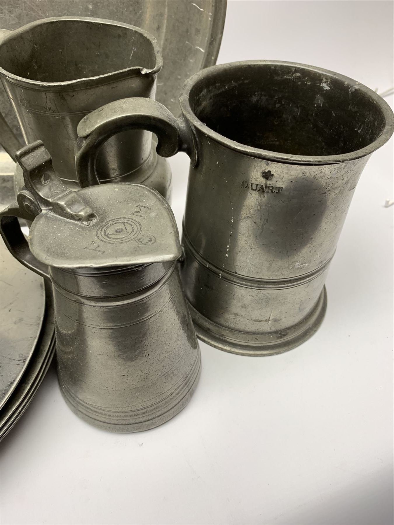 Collection of 18th and 19th century pewter, comprising two chargers, eight large plates, twenty six smaller plates, two bowls, three lidded measures, two jugs, tappit hen, and tankard, the plates with various marks and touch marks, including pseudo 'hallmarks', largest charger 37cm, large plates D30cm, smaller plates D24.5cm, tappit hen H26.5cm