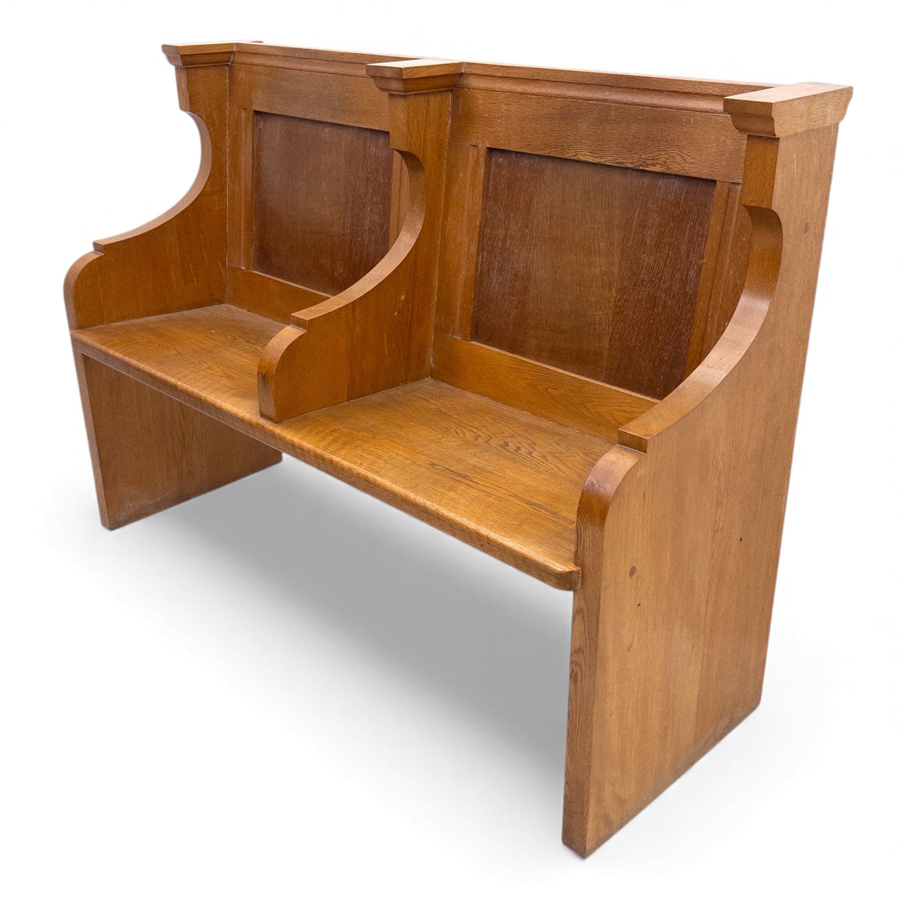 Pair of mid 20th century oak ecclesiastical pews, each with panelled backrests and shaped end supports, of solid construction and mellow honeyed tone