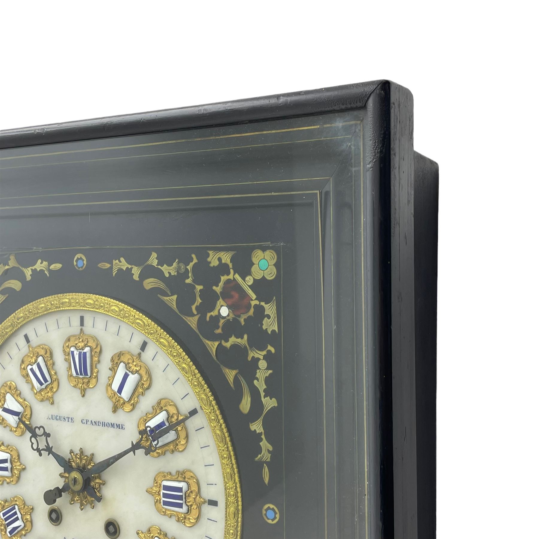 Auguste GP. Andhomme - French vineyard clock,  late 19th century 8-day twin train spring driven wall clock with enamelled and inlaid brass decoration within an ebonised and glazed case, circular enamel dial with cartouche Roman numerals, minute markers, pieced steel hands and a chased brass slip, striking movement, sounding the hours and half hours on a coiled gong. With pendulum and key.  
