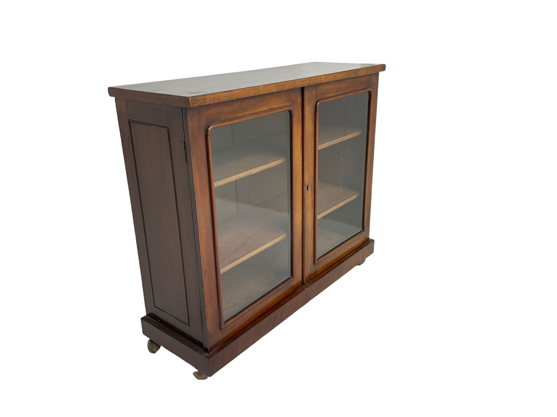 Victorian bookcase, rectangular top over two glazed doors enclosing two shelves, on skirted base