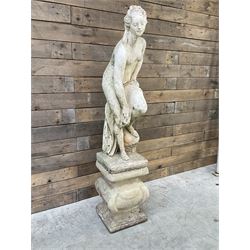 Cast stone garden statue of partially draped classical female figure on ornate pedestal 