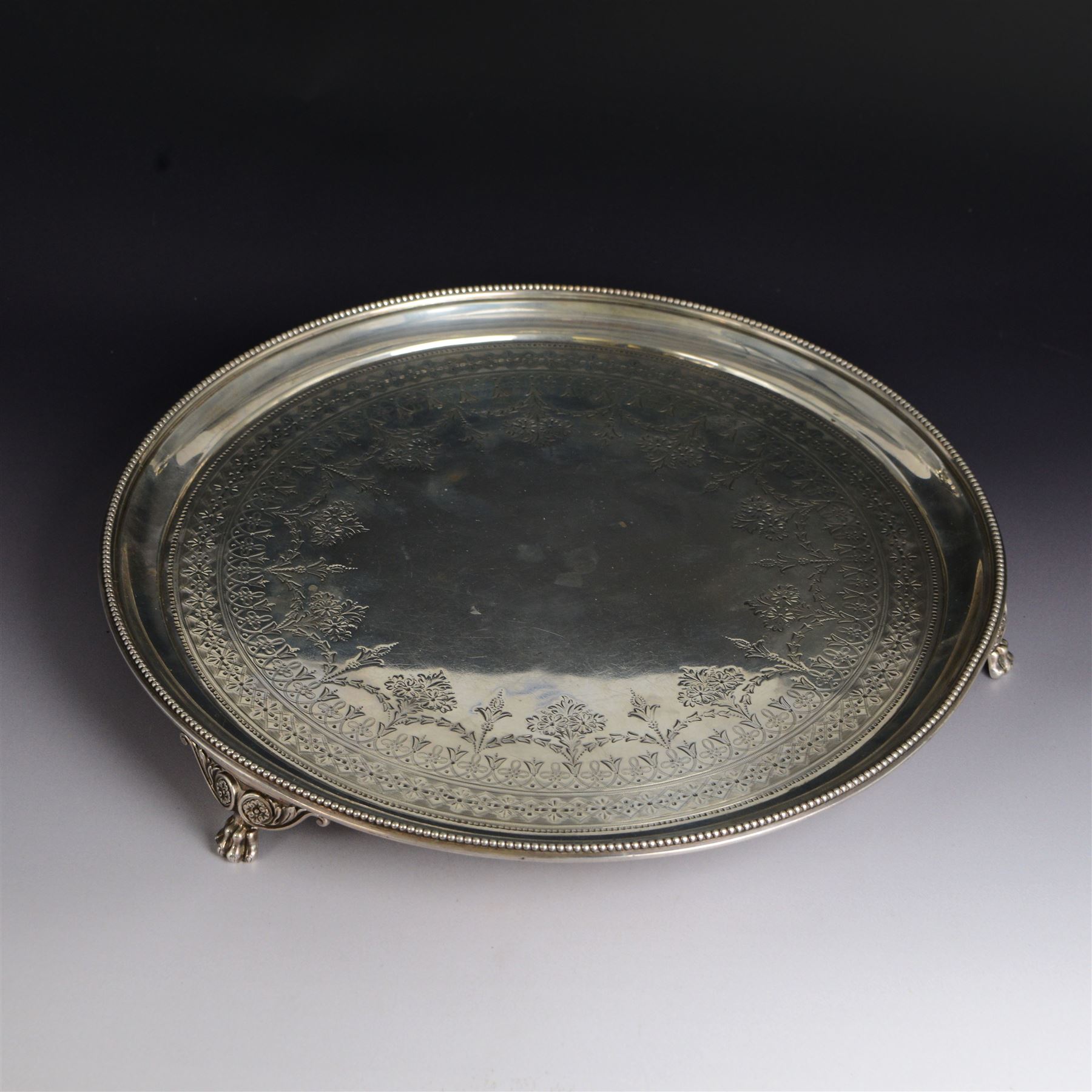 Victorian silver tray, of circular form with beaded rim, engraved to the centre with floral decoration, upon three scroll mounted paw feet, hallmarked Walter & John Barnard, London 1877, D30.5cm