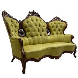 Victorian walnut settee, triple back with pierced and scroll-carved cresting rails over carved fruit and foliage decoration, upholstered in buttoned green fabric, serpentine seat and carved apron, on cabriole feet