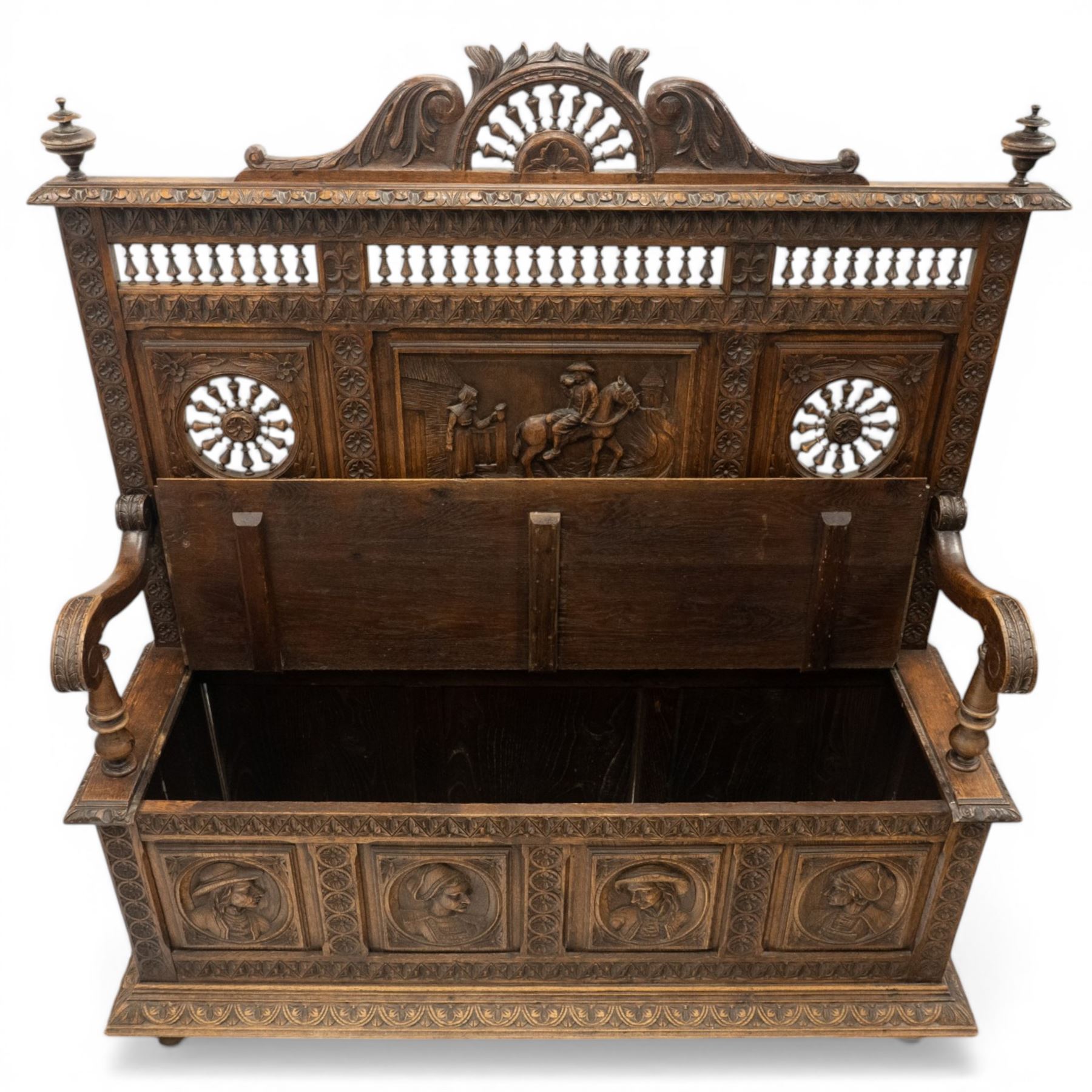 19th century European heavily carved oak hall settle, the impressive high-back with a pierced and carved acanthus pediment, over foliate and rosette carved back rails, flanking a central panel depicting a gentleman on horseback drinking, the hinged box seat over a quadruple panelled front with relief carved busts, lower moulded and carved edge on compressed bun feet