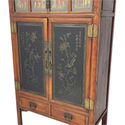 Late 19th century Chinese Qing dynasty red and black lacquered wood cabinet,  Fujianese province, upper cupboard enclosed by two doors with relief carved and gilt panels depicting figures behind glass, the large cupboard enclosed by two panelled doors carved with trailing foliate branches and birds, inscribed with Chinese characters, to the left ‘The red mountains are in the shape of Phoenixes and appear auspicious’ and to the right, ‘Wealth and honour are given by flowers and I hear the sound of the phoenix', fitted with two drawers, on square supports with carved brackets 