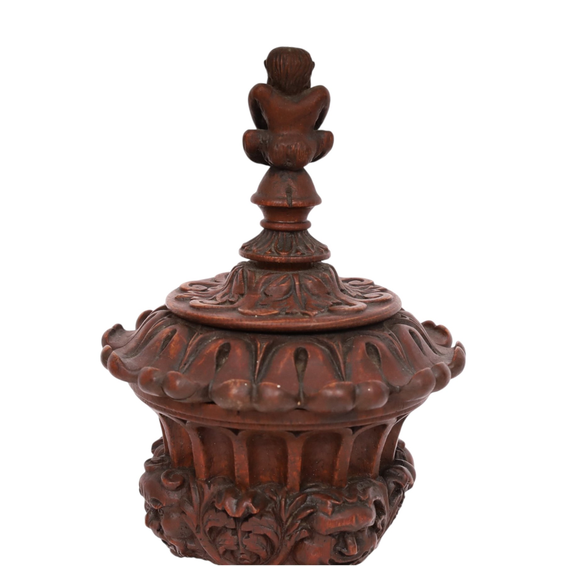Carved wooden urn. decorated in relief with carved faces within foliage, with a Satyr finial, H25cm 