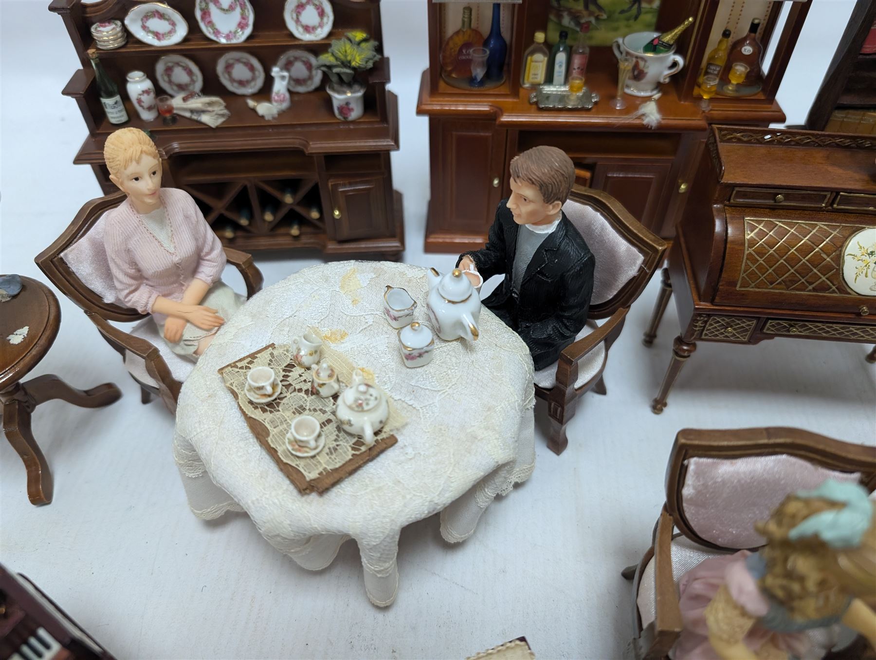 Dolls house drawing room furniture, including dressers, pink and green checked sofa and armchairs, bureau, chairs, piano, eight figures and a collection of afternoon tea miniatures