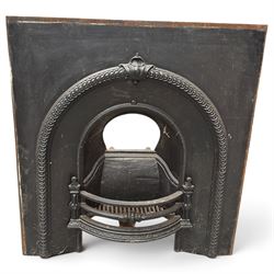 Late Victorian black-painted cast iron fireplace, the arched surround with anthemion cartouche and guilloche-moulded border, enclosing a bow-front fire basket with finialled standards, railed front and leaf-cast apron, with sheet-metal backplate