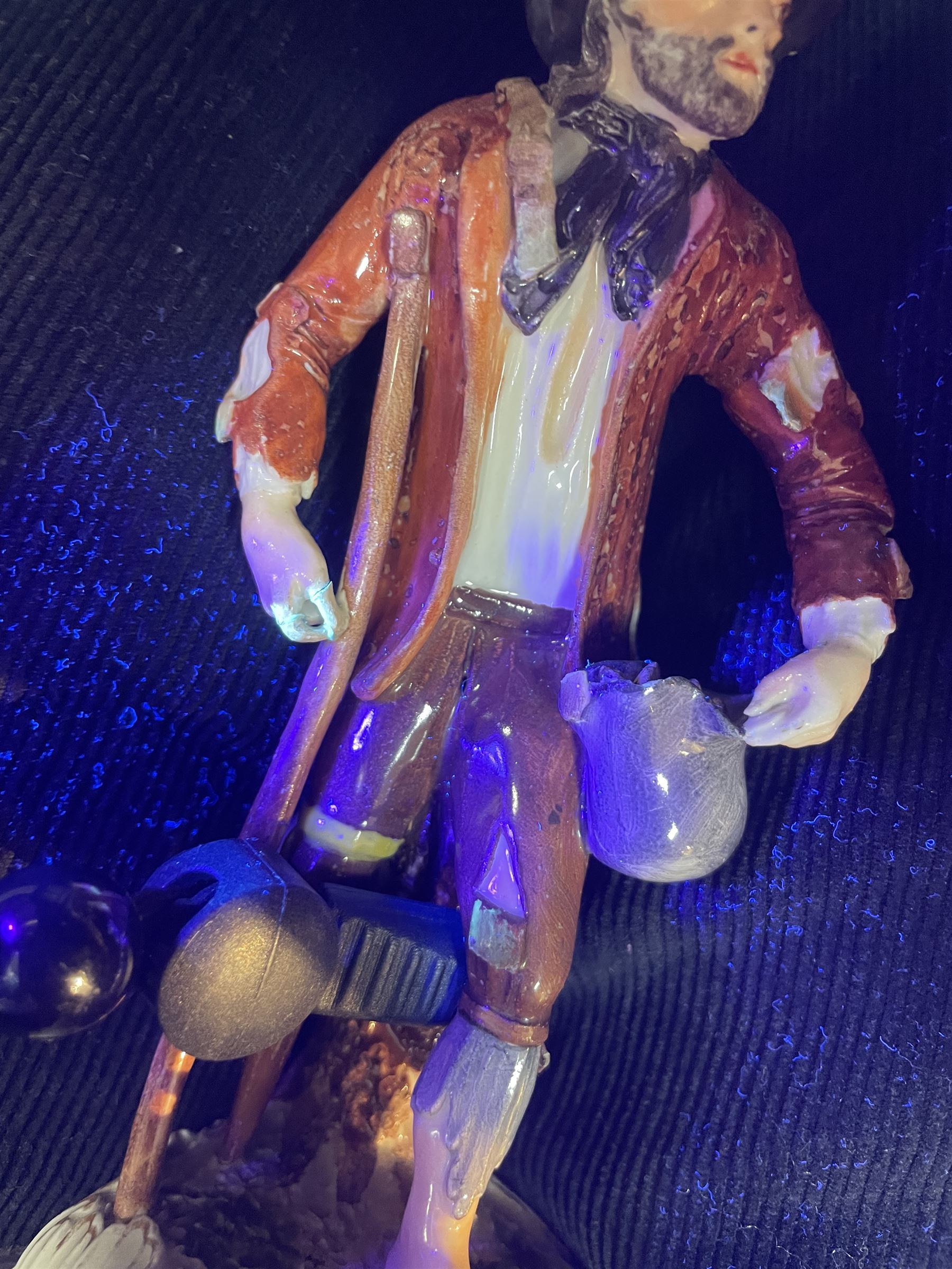 Mid 18th century Furstenberg figure, modelled as a beggar or mendicant with peg leg and bare foot, circa 1755, modelled by Simon Feilner, wearing tattered clothes, one arm supporting an alms pouch, the other holding a crutch, upon a part scrolled base, bearing paper labels beneath including one inscribed 'Sammlung Wilhelm Gumprecht 322', H15cm