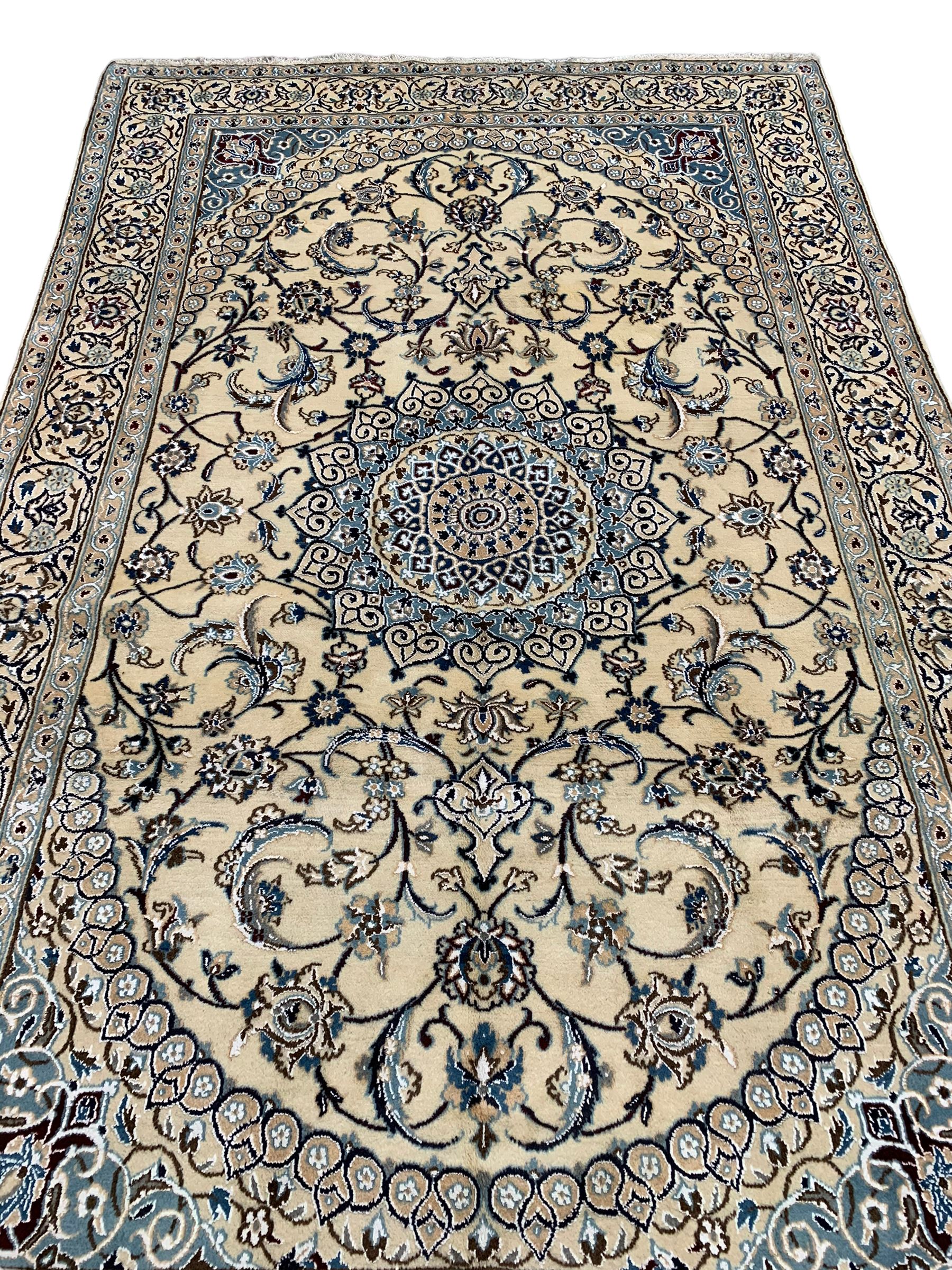 Persian Kashan ivory ground rug, central medallion surrounded by scrolling leafy branches and stylised flowerhead motifs, scrolling border decorated with further stylised plant motifs