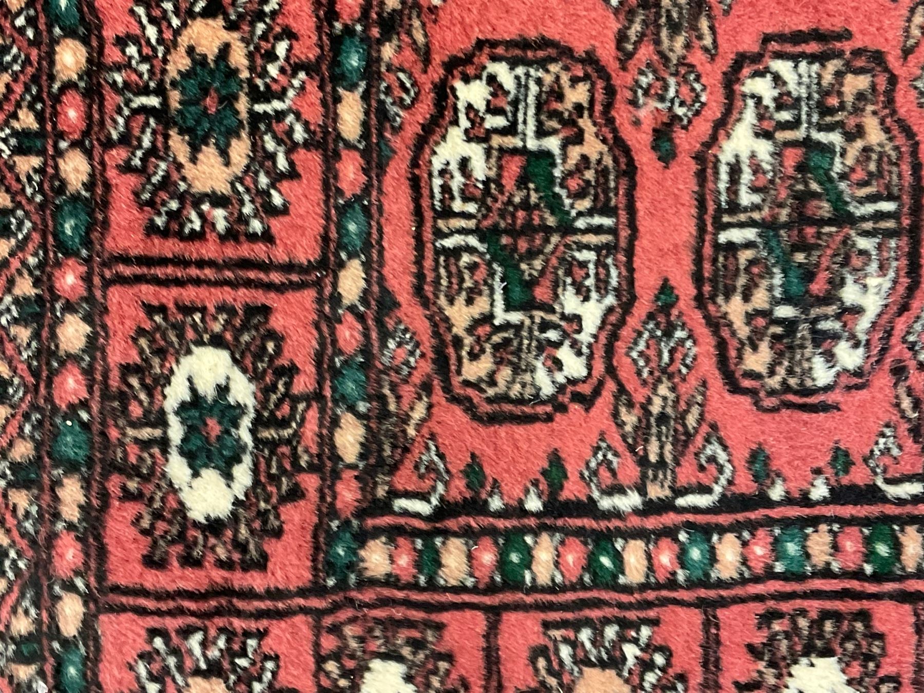 Small peach ground Bokhara rug, decorated with two rows of Gul motifs 
