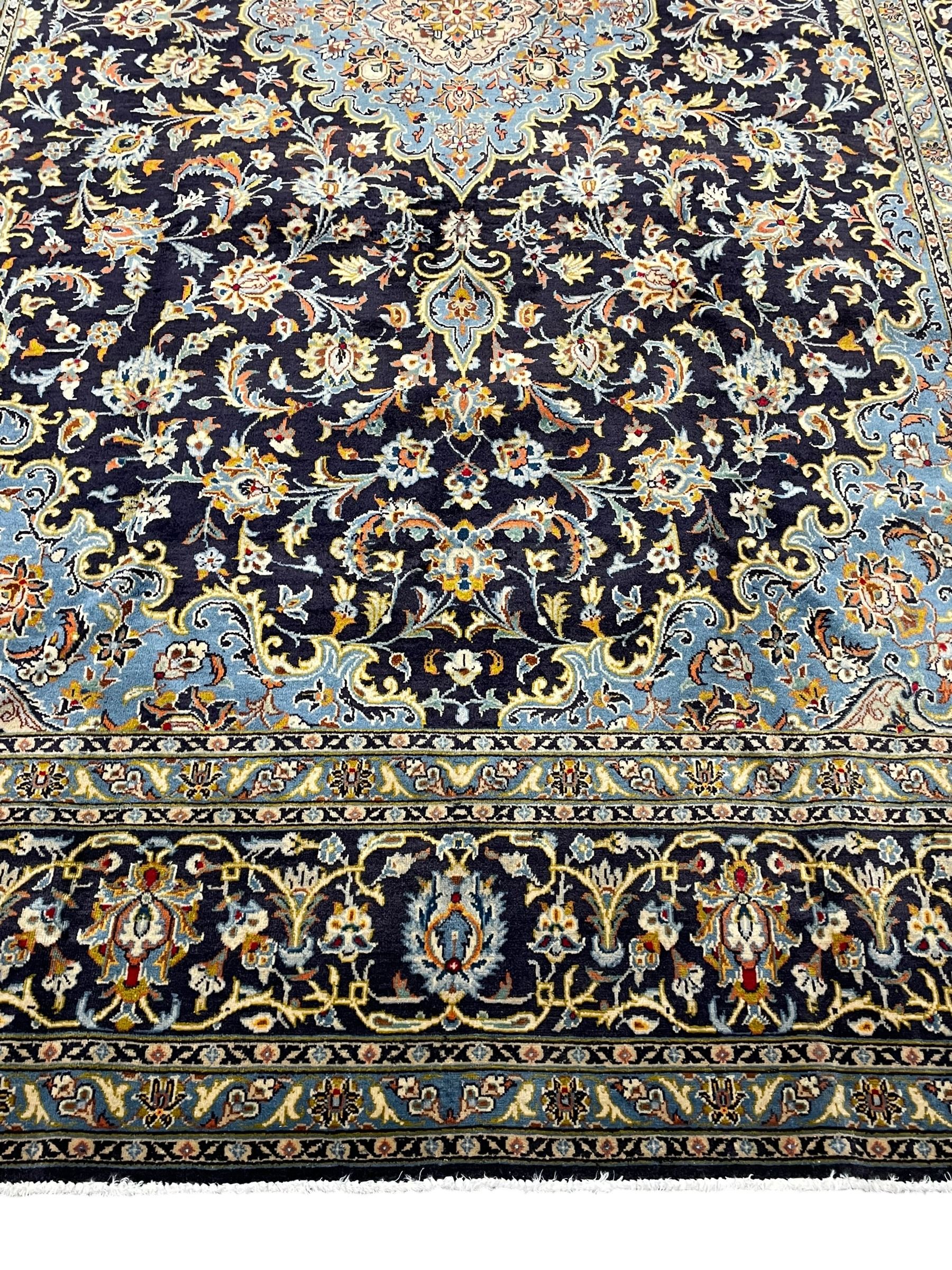 Persian Kashan indigo ground carpet, floral pattern light blue ground central medallion and spandrels, the fielding decorated with interlacing leafy branches and palmettes, the repeating floral pattern border enclosed within guard stripes