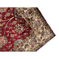 Persian Tabriz crimson ground rug, the field decorated with large palmette and stylised plant motifs connected by interlaced leafy branches, trailing border decorated with similar palmette motifs within floral pattern guard stripes, with signature panel 
