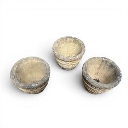 Set of three cast stone planters, circular form with C-scroll design frieze over a floral decorated body, weathered finish