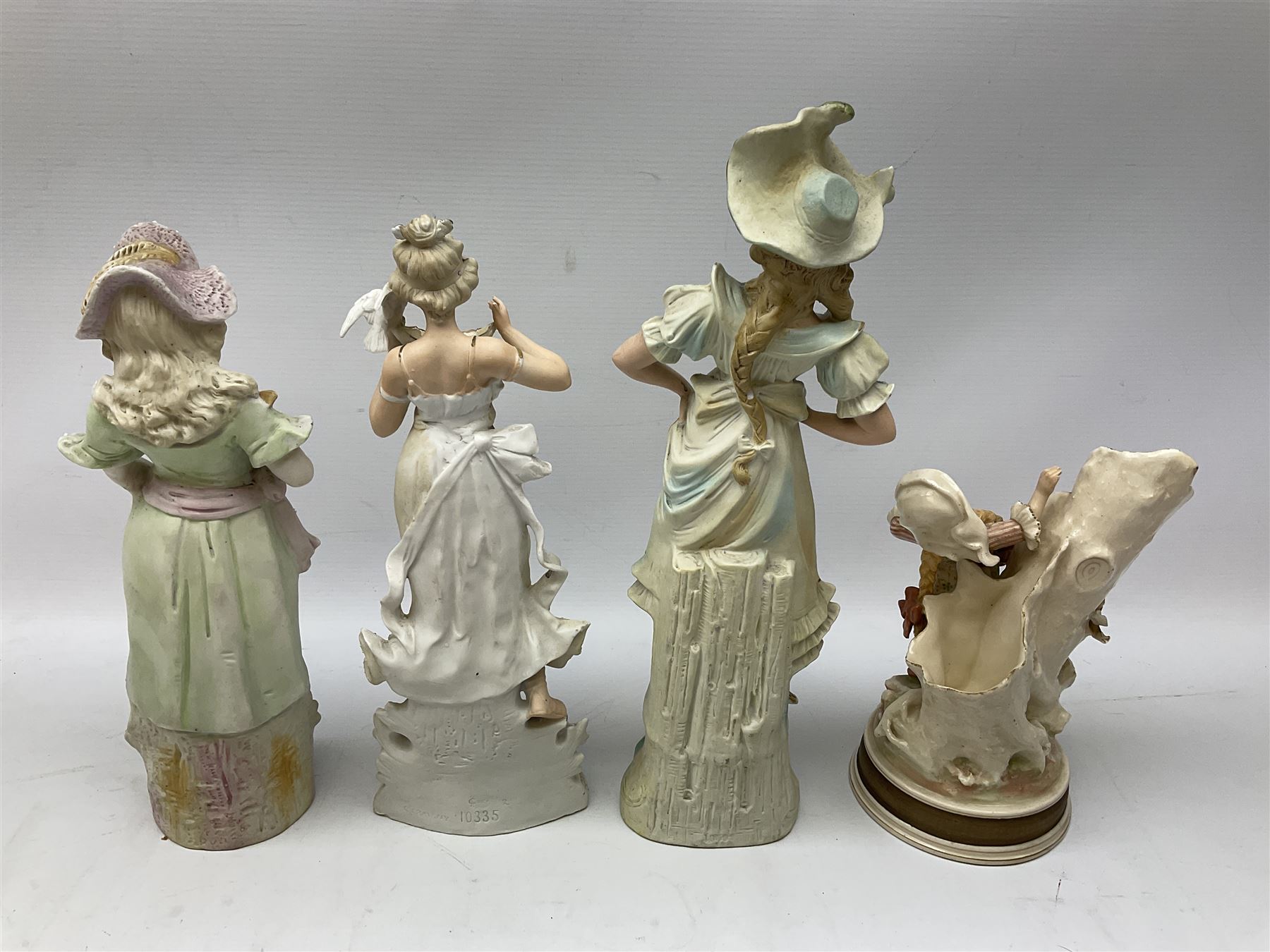 Late 19th century continental spill vase as a young girl standing beside an open tree trunk H21cm; and three German bisque figures (4)