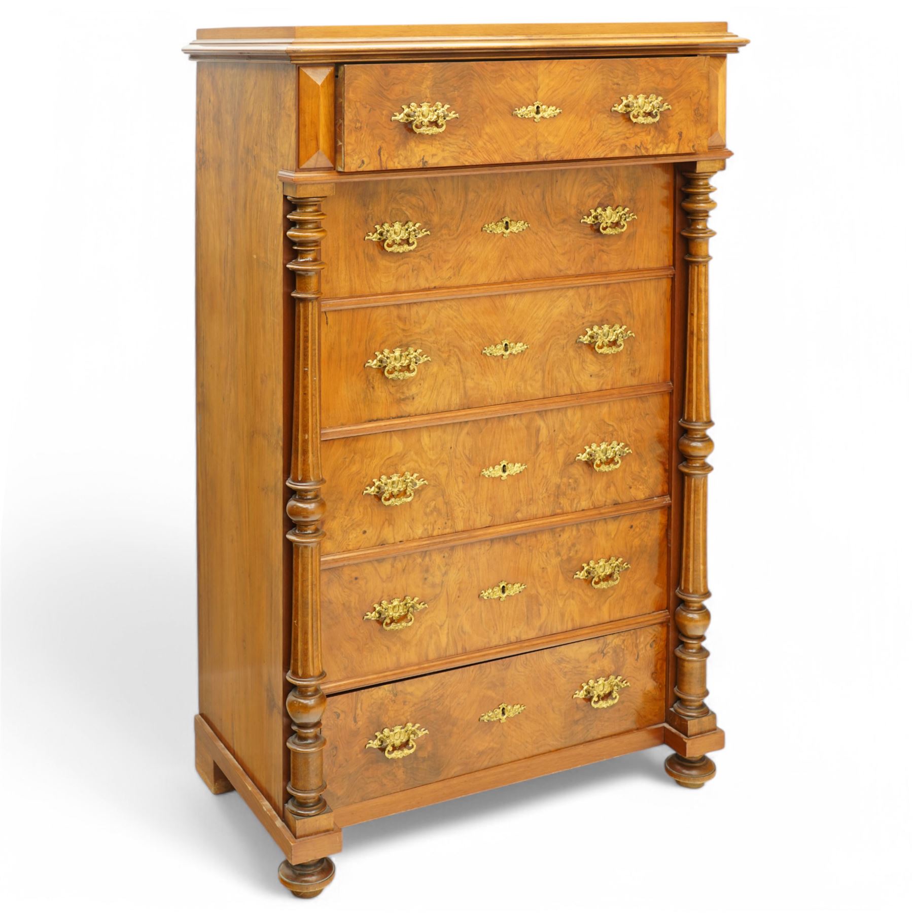 Tall late 19th century walnut chest, stepped and moulded top over six drawers, ornate cast gilt metal handles, enclosed by turned and fluted upright columns, on turned front feet 