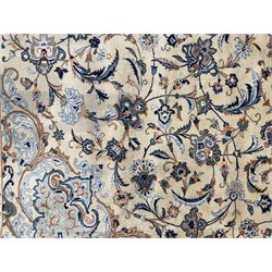 Central Persian Kashan hand-knotted carpet, ivory field with scrolling vines, palmettes, and rosettes around a cusped medallion with pendants and spandrels within a blue ground border of palmettes and flowerheads, 388cm x 300cm