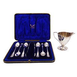 Edwardian silver cream jug, of fluted helmet form, with angular handle and upon shaped foot, hallmarked Birmingham 1905, maker's mark indistinct, together with a set of six Edwardian silver teaspoons and a pair of sugar tongs, all with scrolling embossed decoration and engraved monogram, hallmarked Joseph Rodgers & Sons, Sheffield 1903, within tooled leather fitted case, jug including handle H9cm 