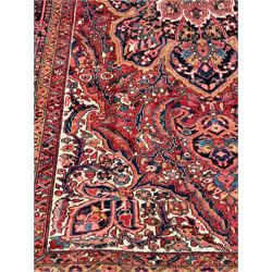 Antique Persian coral ground carpet, the large central floral pole medallion with extending foliate designs, the thick guarded indigo border with repeating flower heads and circles