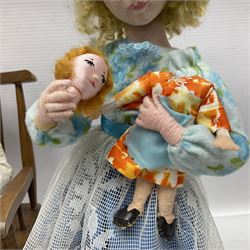 Anna Meszaros Hungary - three hand made needlework figurines - 'The Cobbler' as a child seated in a wooden rocking chair working on a removed boot H24cm; young girl standing crying holding a doll with broken head H32cm; and young girl in long dress and bonnet standing holding a doll H27cm (3)  Auctioneer's Note: Anna Meszaros came to England from her native Hungary in 1959 to marry an English businessman she met while demonstrating her art at the 1958 Brussels Exhibition. Shortly before she left for England she was awarded the title of Folk Artist Master by the Hungarian Government. Anna was a gifted painter of mainly portraits and sculptress before starting to make her figurines which are completely hand made and unique, each with a character and expression of its own. The hands, feet and face are sculptured by layering the material and pulling the features into place with needle and thread. She died in Hull in 1998.