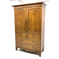 Early 19th century oak linen press cupboard, the projecting cornice over two panelled doors enclosing shelves, two short and two long drawers below, bracket feet