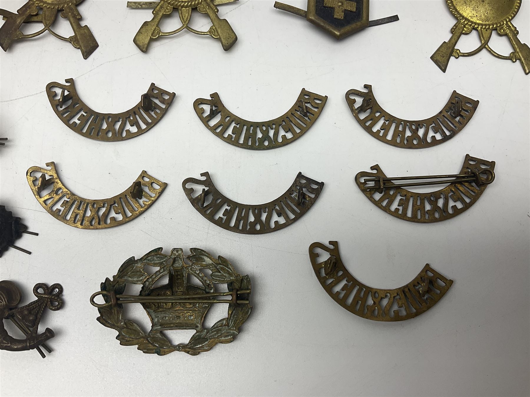 Over thirty British and Continental military metal badges; together with quantity of shoulder titles, collar dogs, rank pips, uniform buttons etc