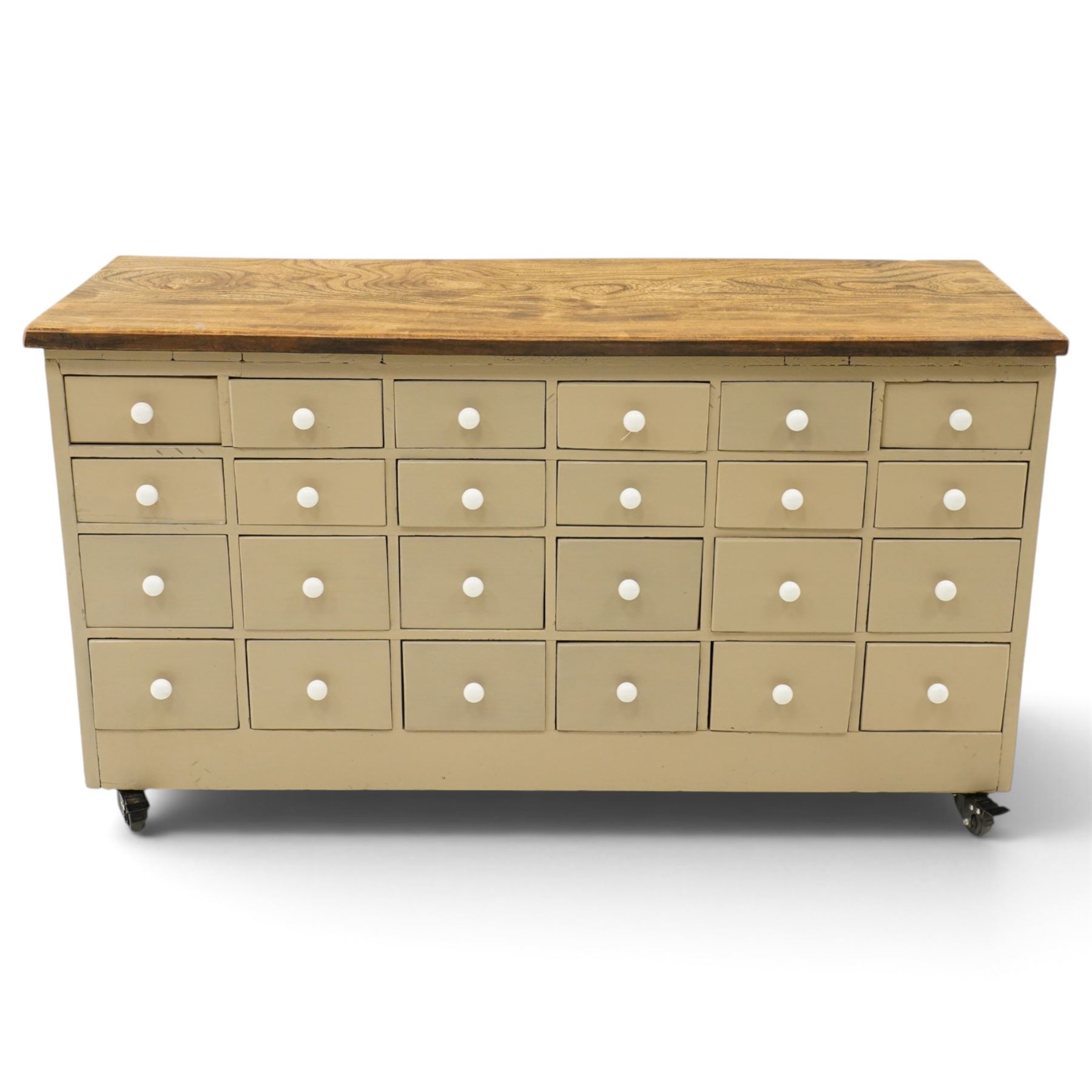 20th century haberdashery style chest, solid elm top over twenty-four assorted drawers with white ceramic knob handles, painted sage green carcass, raised on castors