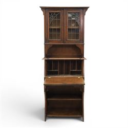 Arts & Crafts oak bureau bookcase, projecting cornice with leaded and glazed upper cabinet, the lower section with fall front section revealing a fitted interior, above shaped lower shelving 