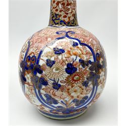 Pair of late 19th century Japanese Imari porcelain bottle vases with covers, painted with shaped reserves of peonies, chrysanthemums and prunus blossom, against a foliate and diaper ground, heightened with gilt throughout, each with character mark beneath, H32cm