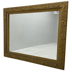 Rectangular gilt framed wall mirror, decorated with trailing leafy branches and flowers heads, plain mirror plate