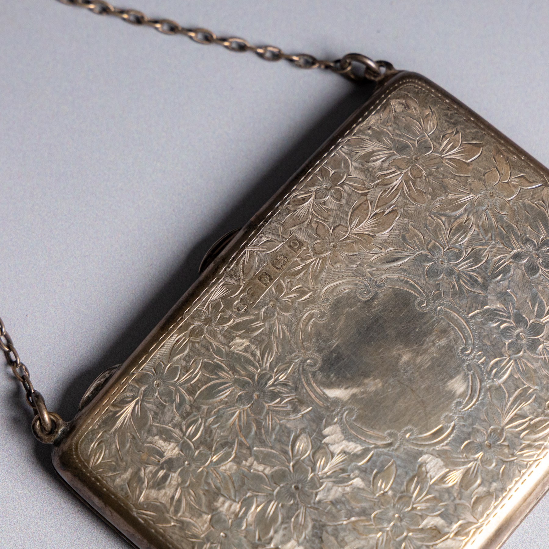Early 20th century silver coin purse, with floral decoration and finger chain, hallmarked together with an early 20th century cigarette case,  with engraved initials, hallmarked and a silver filigree cigarette case