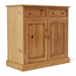 Contemporary pine storage cabinet, the rectangular top with rounded corners, over twin drawers and panelled cupboard doors, fitted with turned knob handles, plinth base