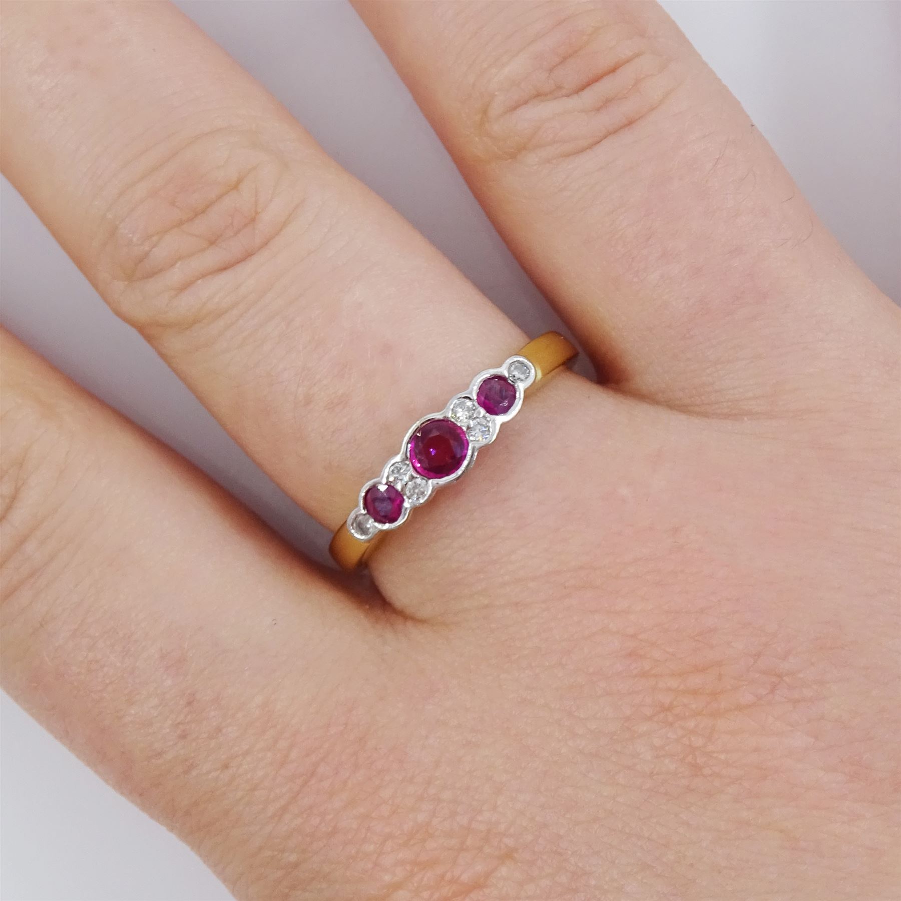 18ct gold ruby and diamond ring, three round cut rubies, with round brilliant cut diamonds set between, London import mark 1995, total diamond weight 0.07 carat, total ruby weight approx 0.70 carat