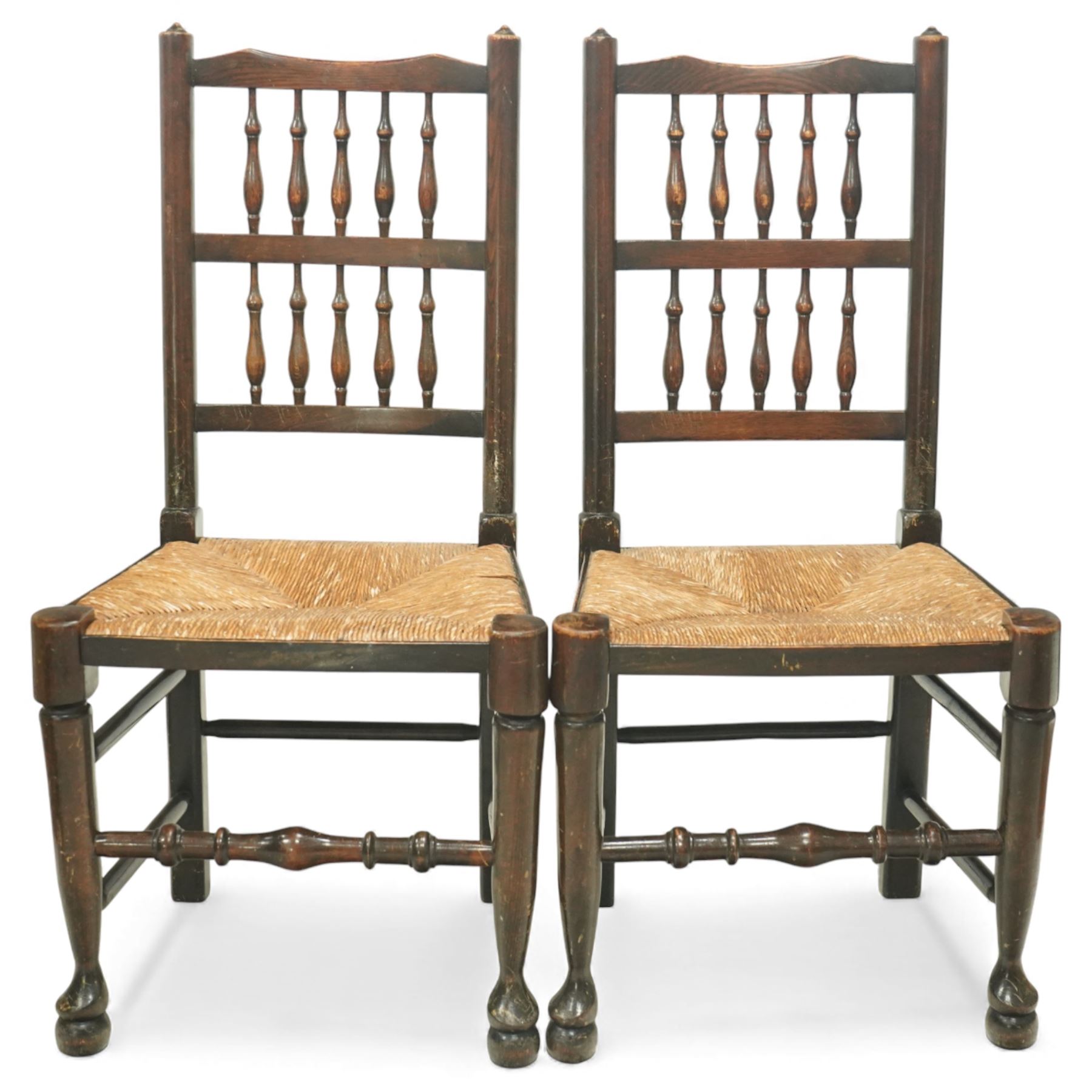 20th century set of five spindle-back dining chairs, with shaped top rails above turned spindle splats, rush seats, turned forelegs united by stretchers