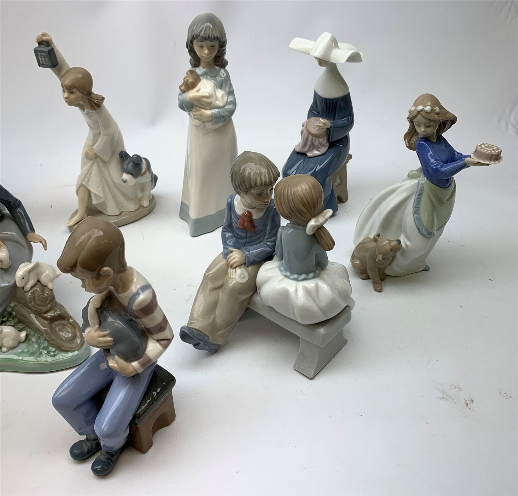 A group of thirteen Nao figurines, together with one Lladro figurine, each with printed mark beneath. 