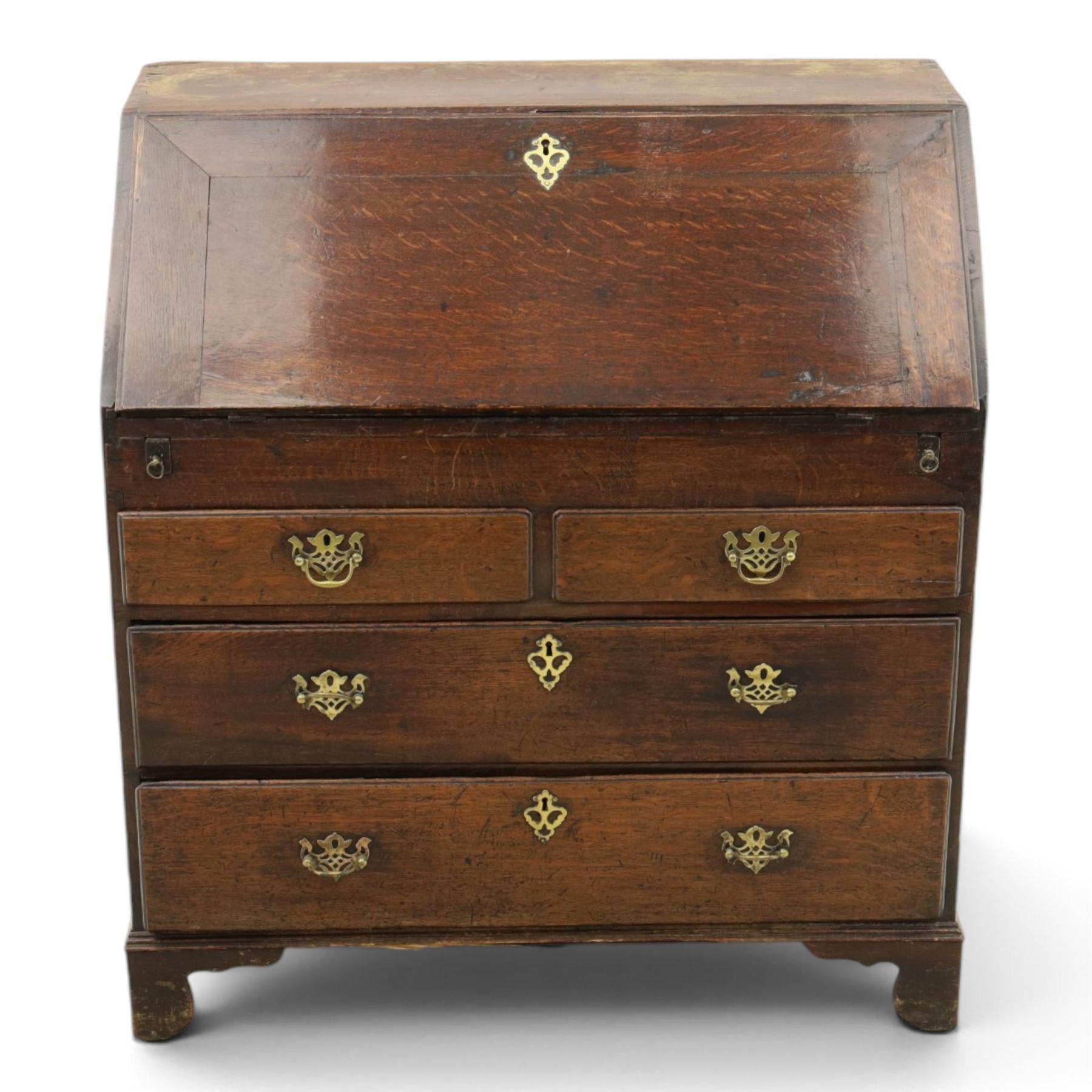 Georgian oak bureau, fall front with pierced brass escutcheon and handles, revealing a fitted interior, above two short over two long drawers, raised on bracket feet