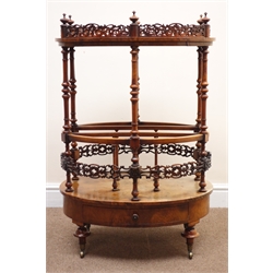  Victorian figured walnut oval Canterbury, pierced galleried top with turned finials, three division base with pierced band and single drawer on mushroom turned supports with brass sockets and castors, W63cm, D45cm, H93cm  