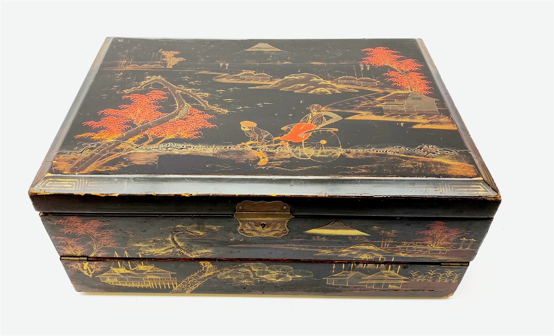  A 20th century Chinese black lacquer and gilt detailed writing box, decorated with figures, pagodas and cranes amidst a mountainous landscape, the hinged cover opening to reveal a compartmented interior and fold out baize lined slope, H20cm L46.5cm D31.5cm.   