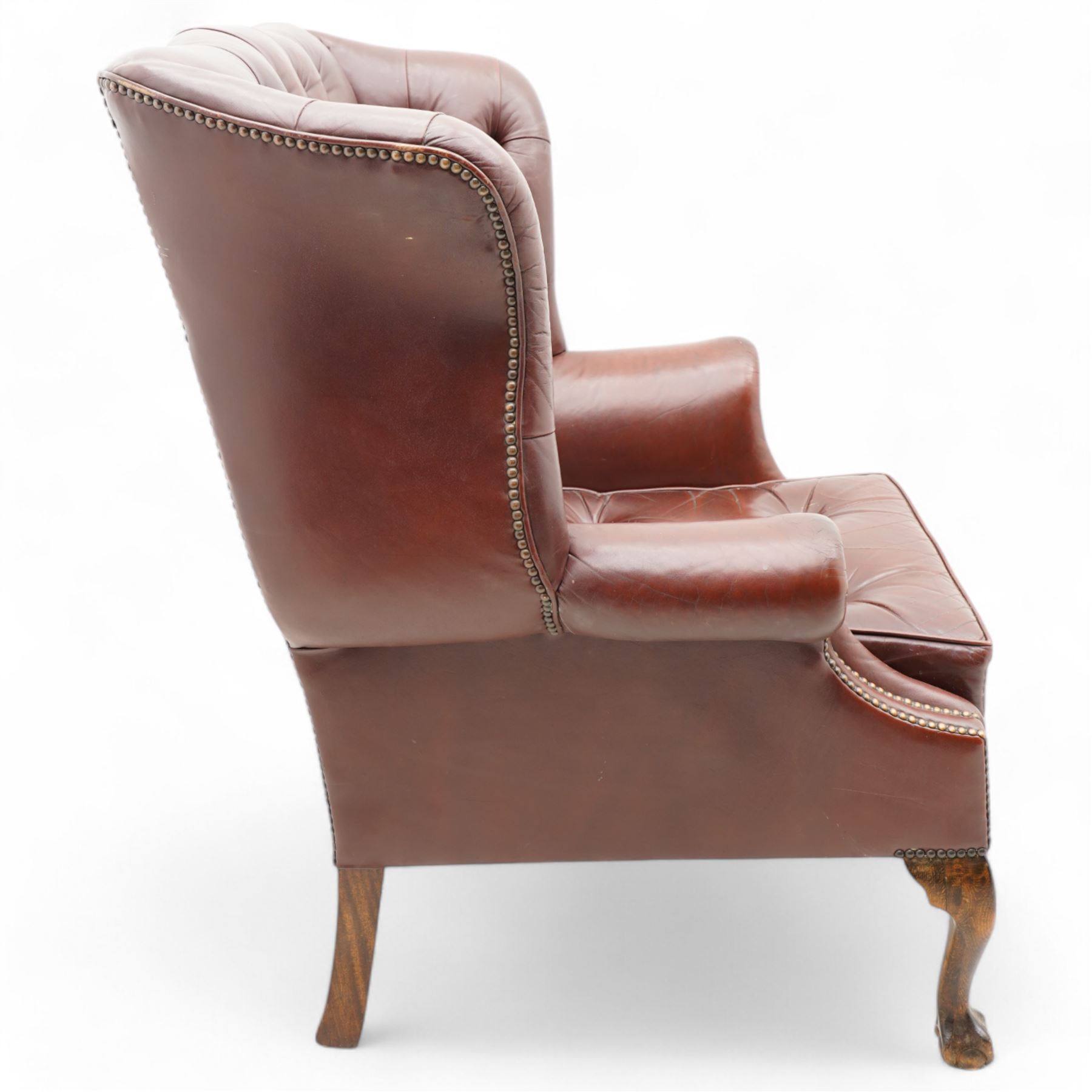 Georgian design leather wingback armchair, deep-buttoned burgundy leather upholstery with rolled arms, studded detail along the edges, raised on cabriole supports terminating in claw and ball feet

