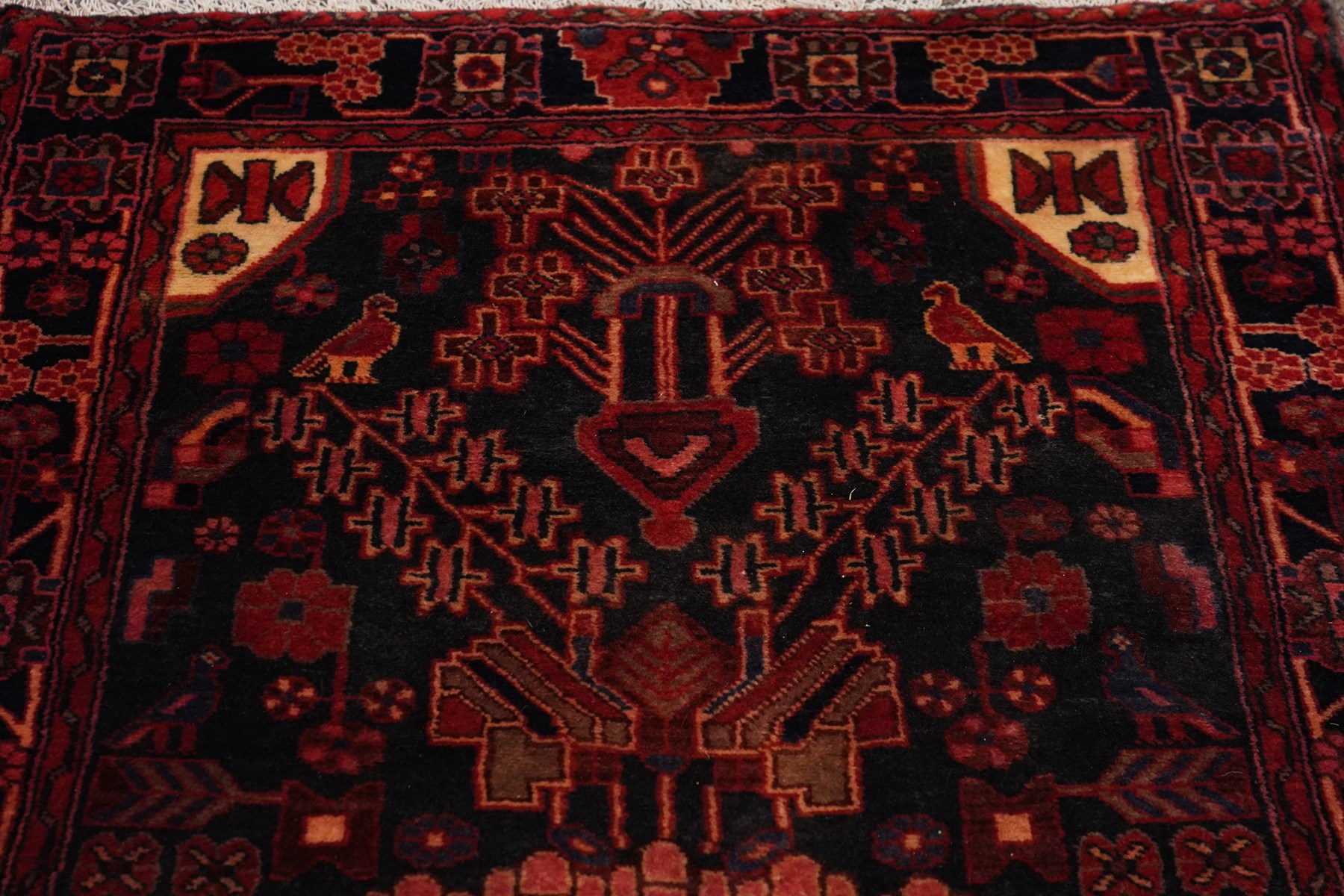 Persian Hamadan runner rug, the indigo ground decorated with stylised flowering plants and geometric motifs in crimson, rose and ivory, enclosed by an indigo flowerhead border and narrow red guard stripes