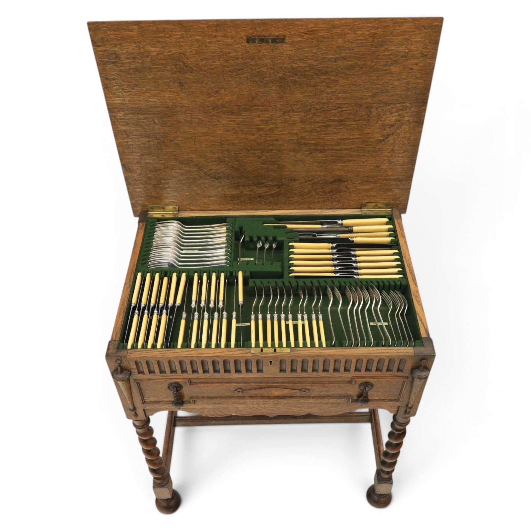 Early 20th century oak cased canteen on barleytwist stand, hinged top with fitted baized lined interior, above a drawer fitted for cutlery