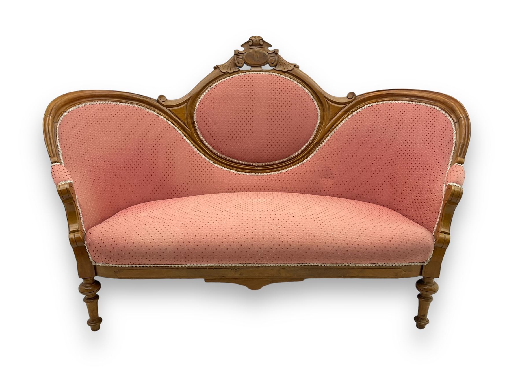 Late Victorian walnut framed double spoon back sofa, shaped crest rail with central carved medallion over curved back with pink upholstery, scrolling arms with additional carvings, on turned supports