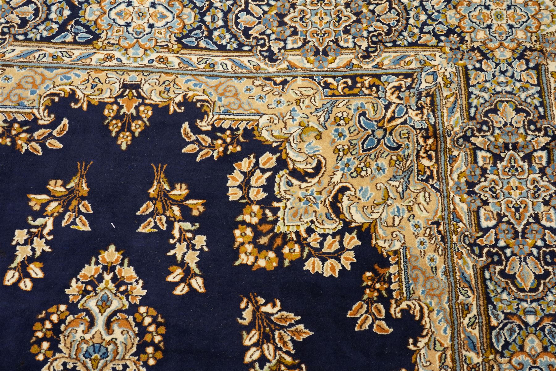 South East Persian Kirman hand-knotted carpet, indigo blue field with central floral medallion in tones of ivory, indigo,  and soft blue, issuing network of scrolling vinery, palmettes and floral sprays, conforming spandrels, broad main border of scrolling foliage and stylized palmettes, framed by multiple guard borders, with cotton fringe ends 