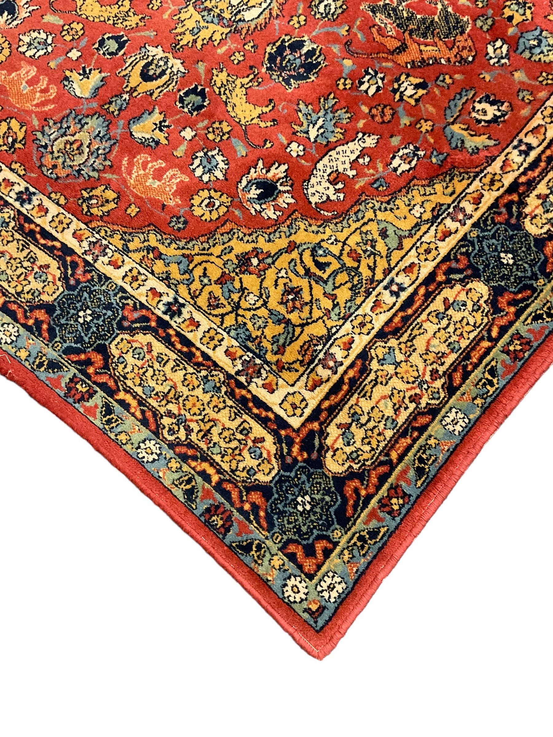 Persian design red ground rug, decorated with plant and animal motifs, the border decorated with floral design panels with guards