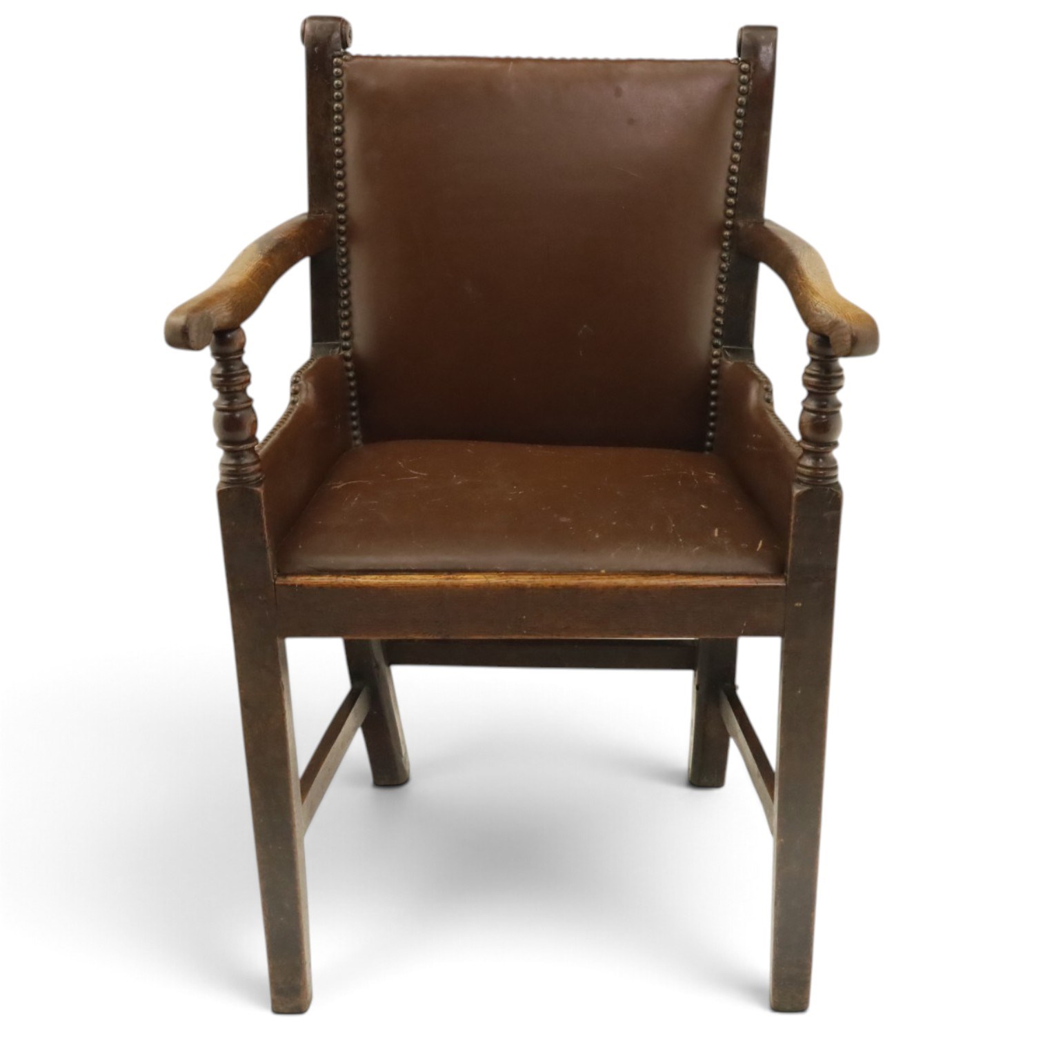 DD CL - Early 20th century oak open armchair, rectangular back with scrolled uprights, brown upholstered back and seat with brass stud edging, shaped open arms on turned supports, square legs united by stretchers