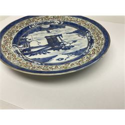 Late 19th century Chinese rice plate, of circular form decorated with underglaze blue landscape featuring figure on bridge before pagodas, heightened with gilt and contained within blue diaper borders and foliate polychrome enamel border, with Guangxu six character mark beneath, D21cm