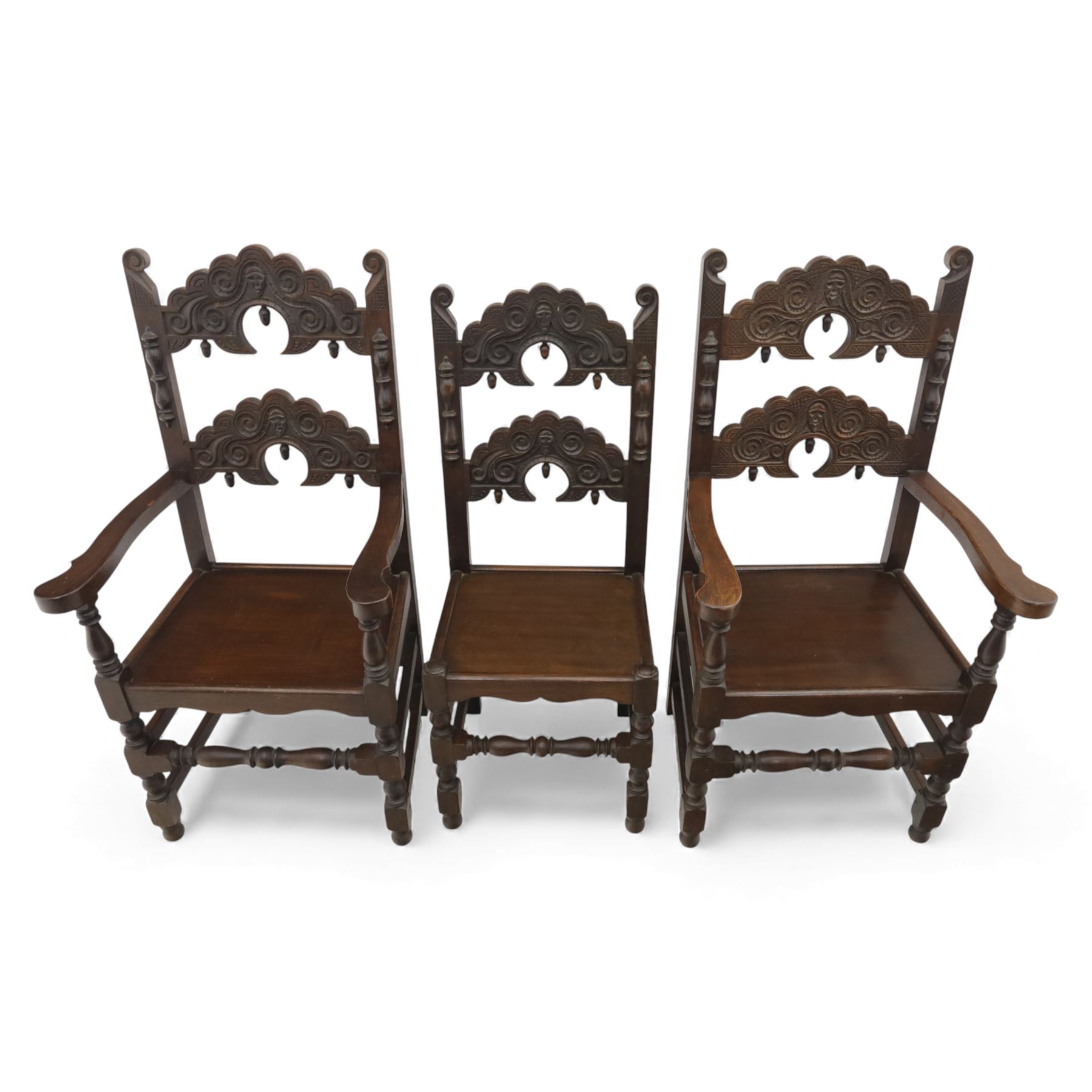 Early 20th century set of seven Jacobean Revival oak chairs, comprising pair of cavers and five chairs, each with carved mask and scroll decoration to the crest and and back rail, plain oak seat, upon turned front legs and block rear legs with conforming stretchers