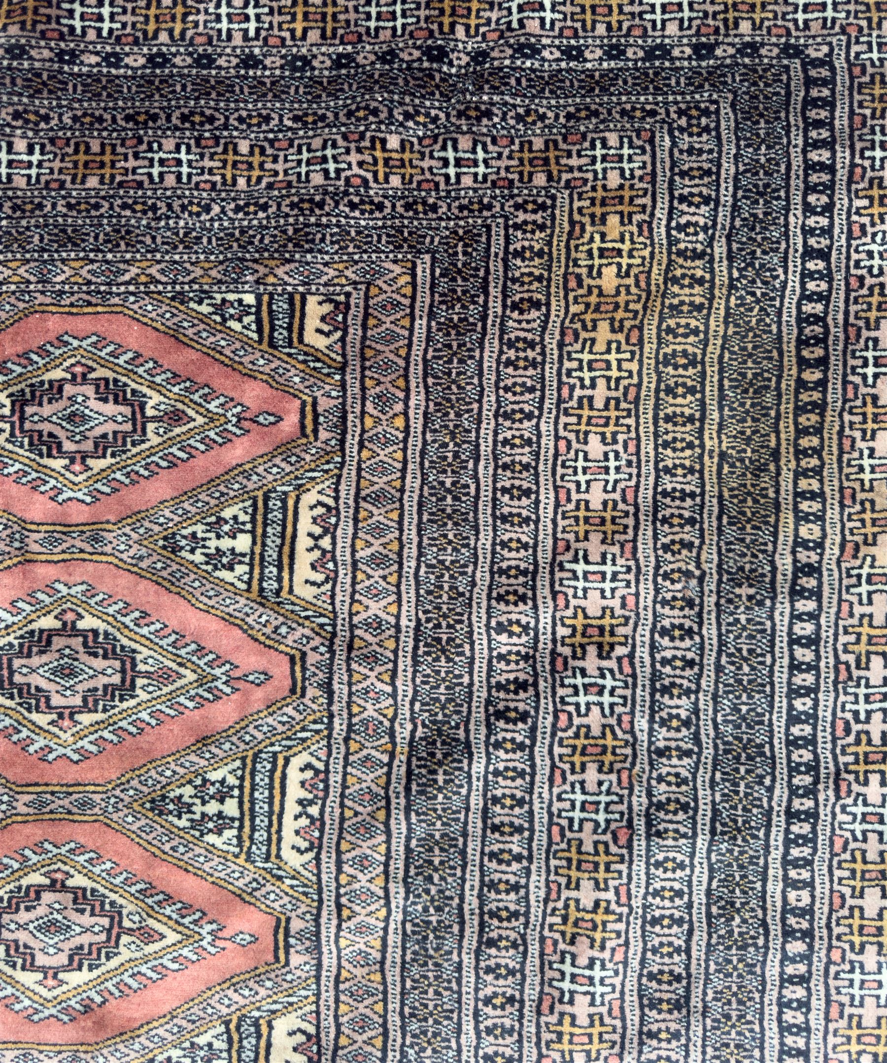 Large Persian Bokhara wool rug, the field decorated with repeating gul motifs in lozenge medallions across a dark ground, enclosed by multiple geometric borders in indigo, ivory and terracotta, from the region of Baluchistan