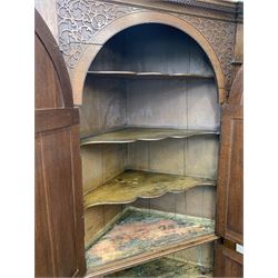 Large George III oak corner cupboard, projecting cornice over two stepped arch doors with fielded panels and blind fret work spandrels, flanked by fluted uprights, cupboard below enclosed by two fielded panel doors, the painted interior fitted with shaped shelves
 